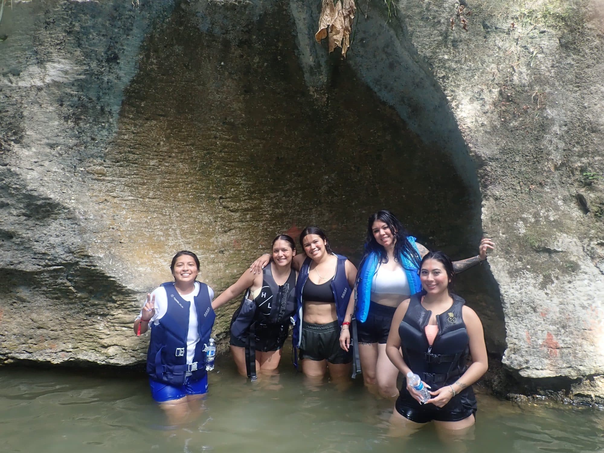Group in life vests at a river cave entrance