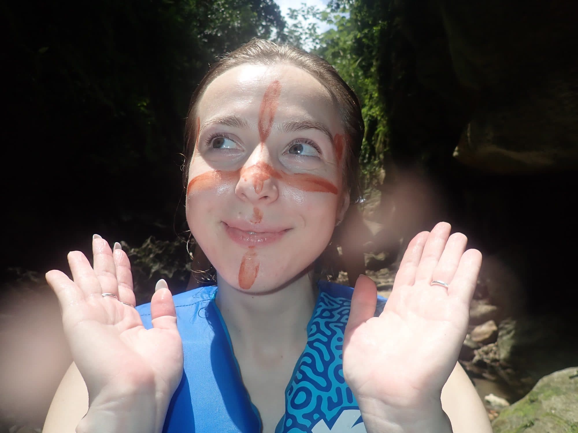 Smiling guest with face paint in a river cave