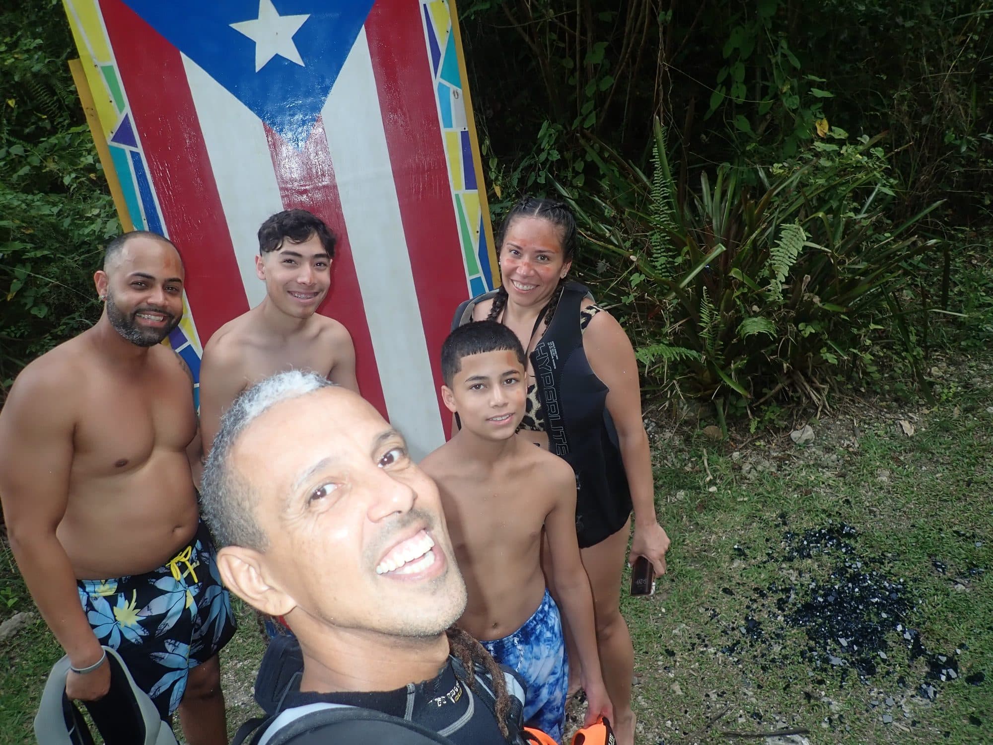 Jesús and a family by a Puerto Rican flag on the trail