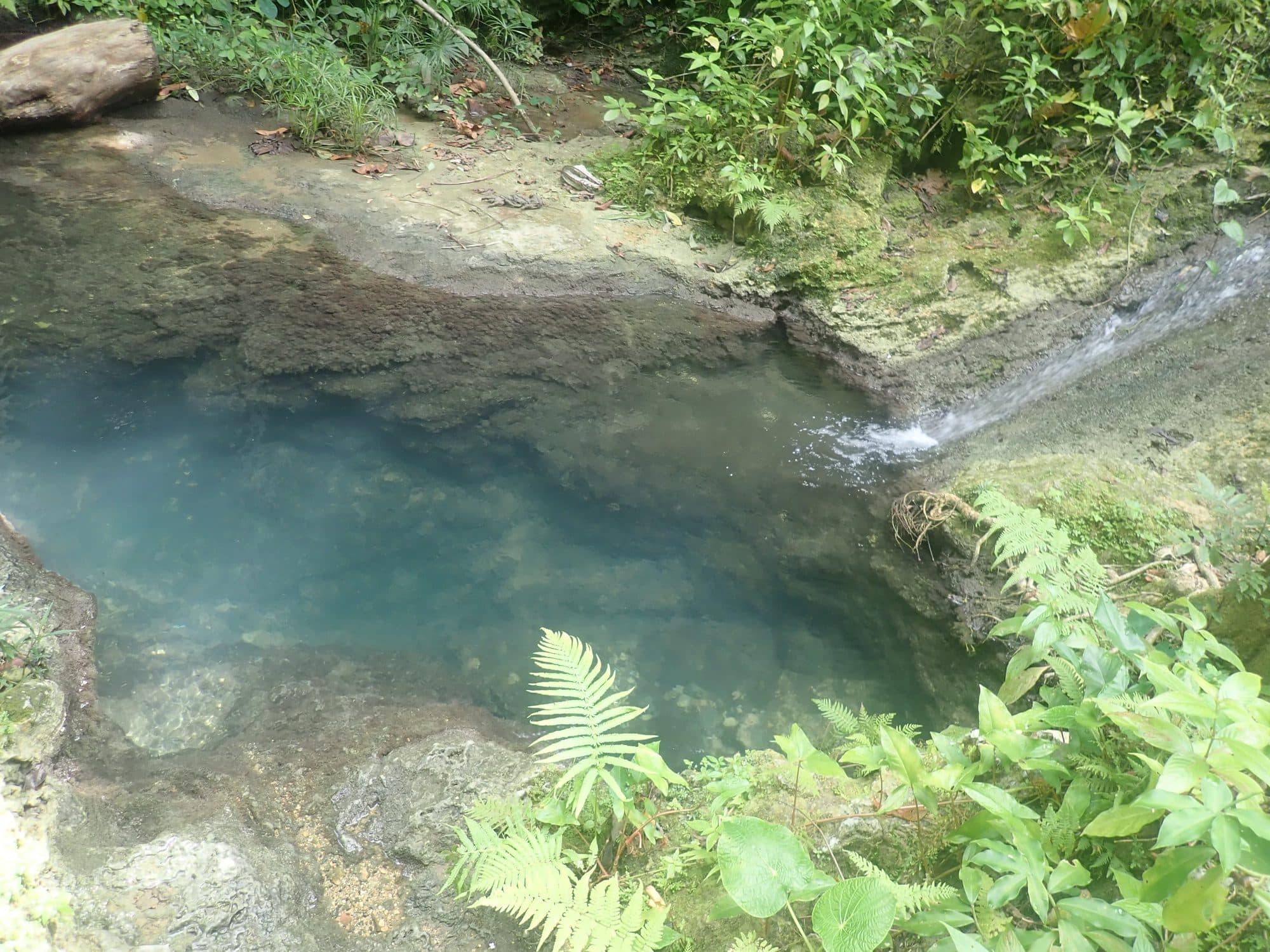 Turquoise pool fed by a small waterfall