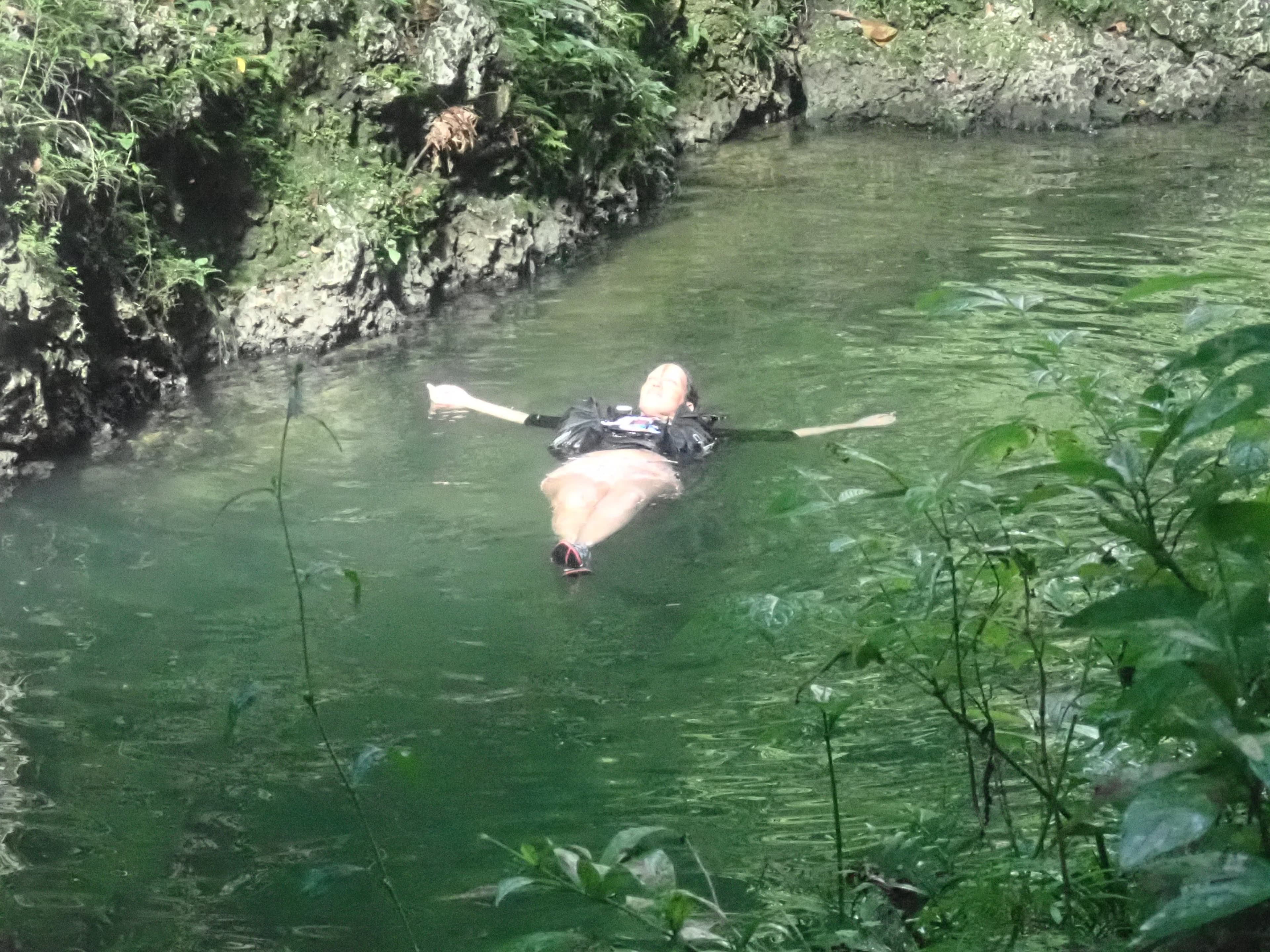 Swimmer floating on his back in a green river pool