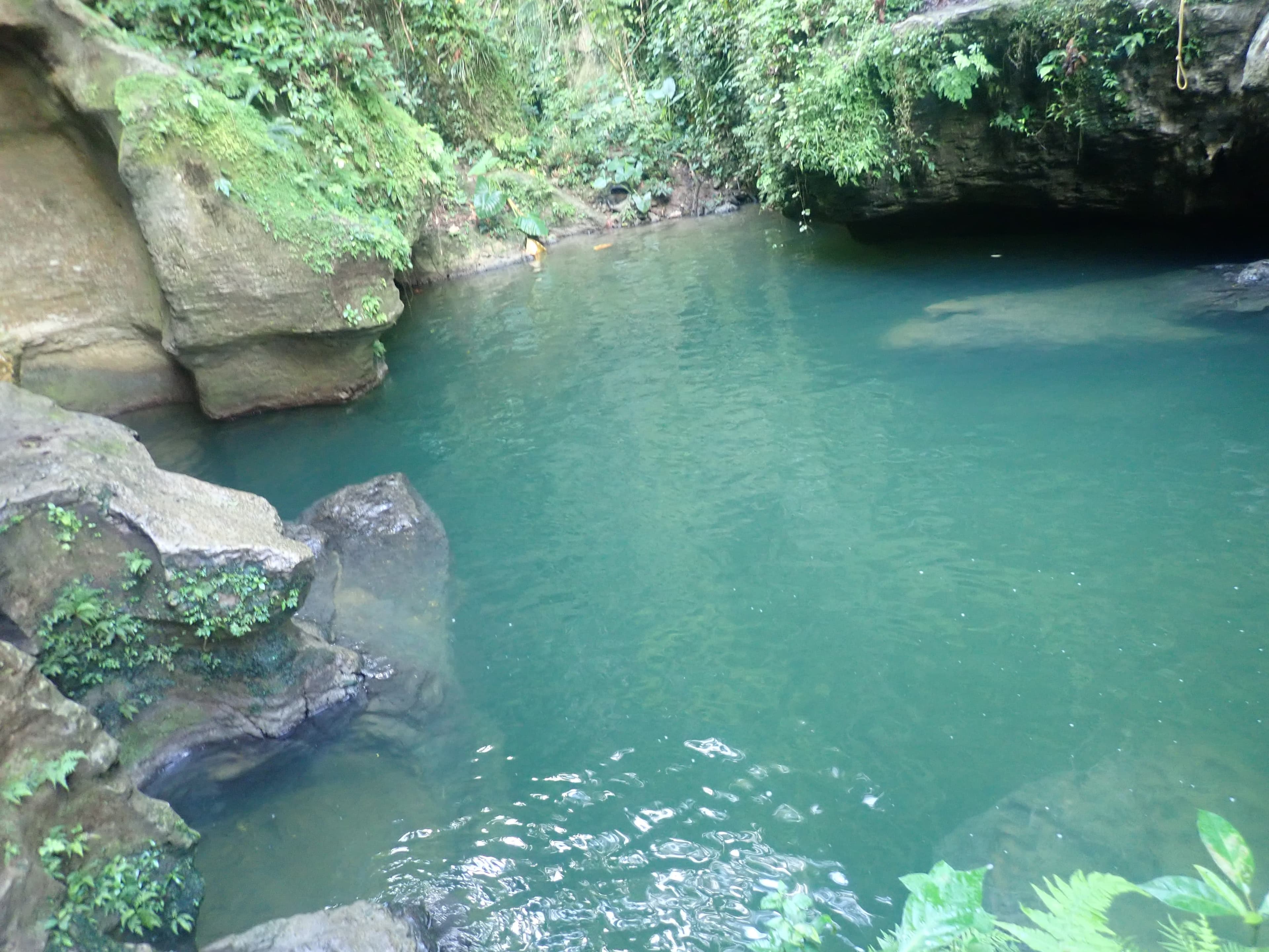 Turquoise river pool below limestone rocks at Charco Azul