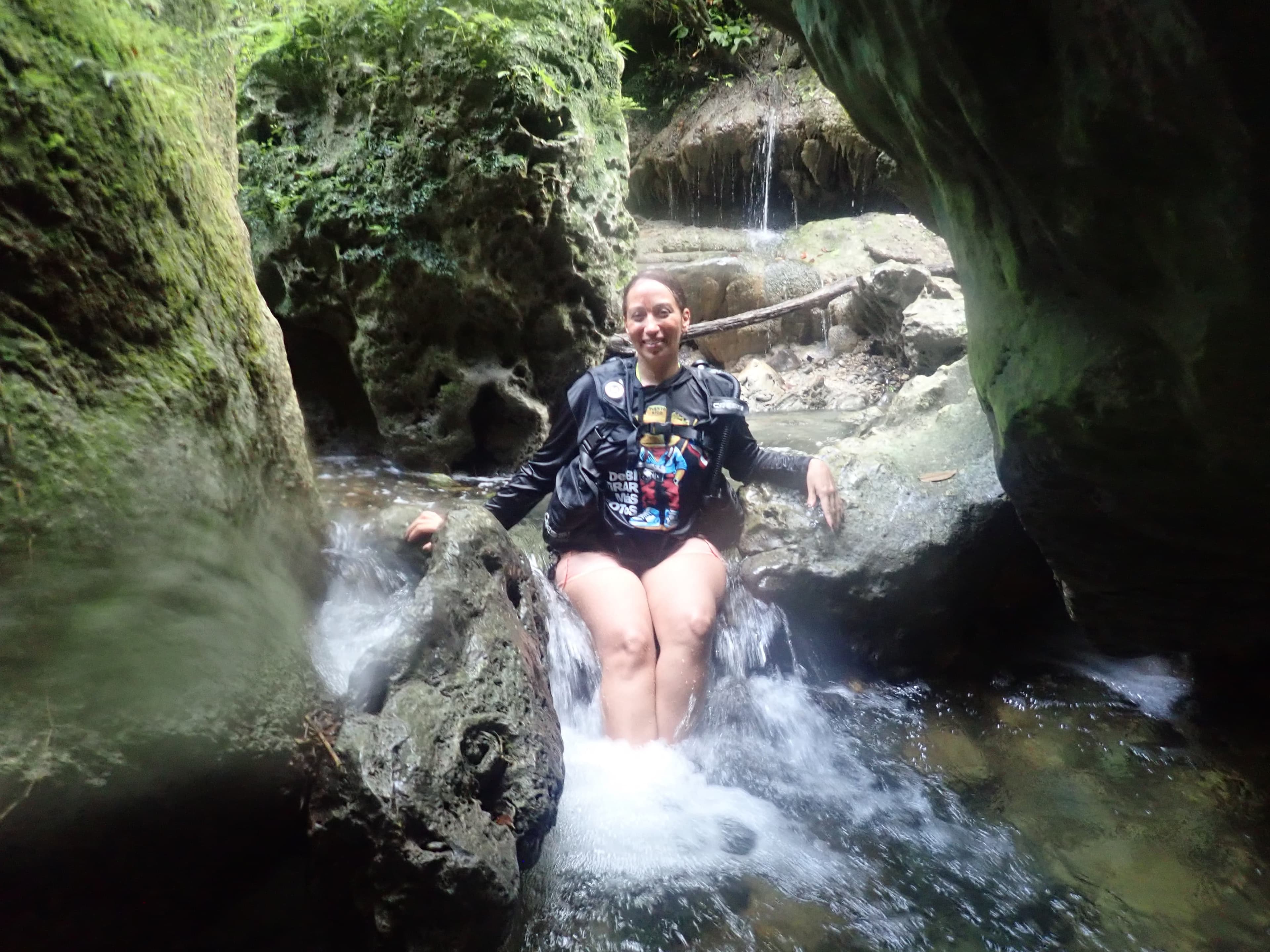 Guest sitting in a small waterfall inside the canyon