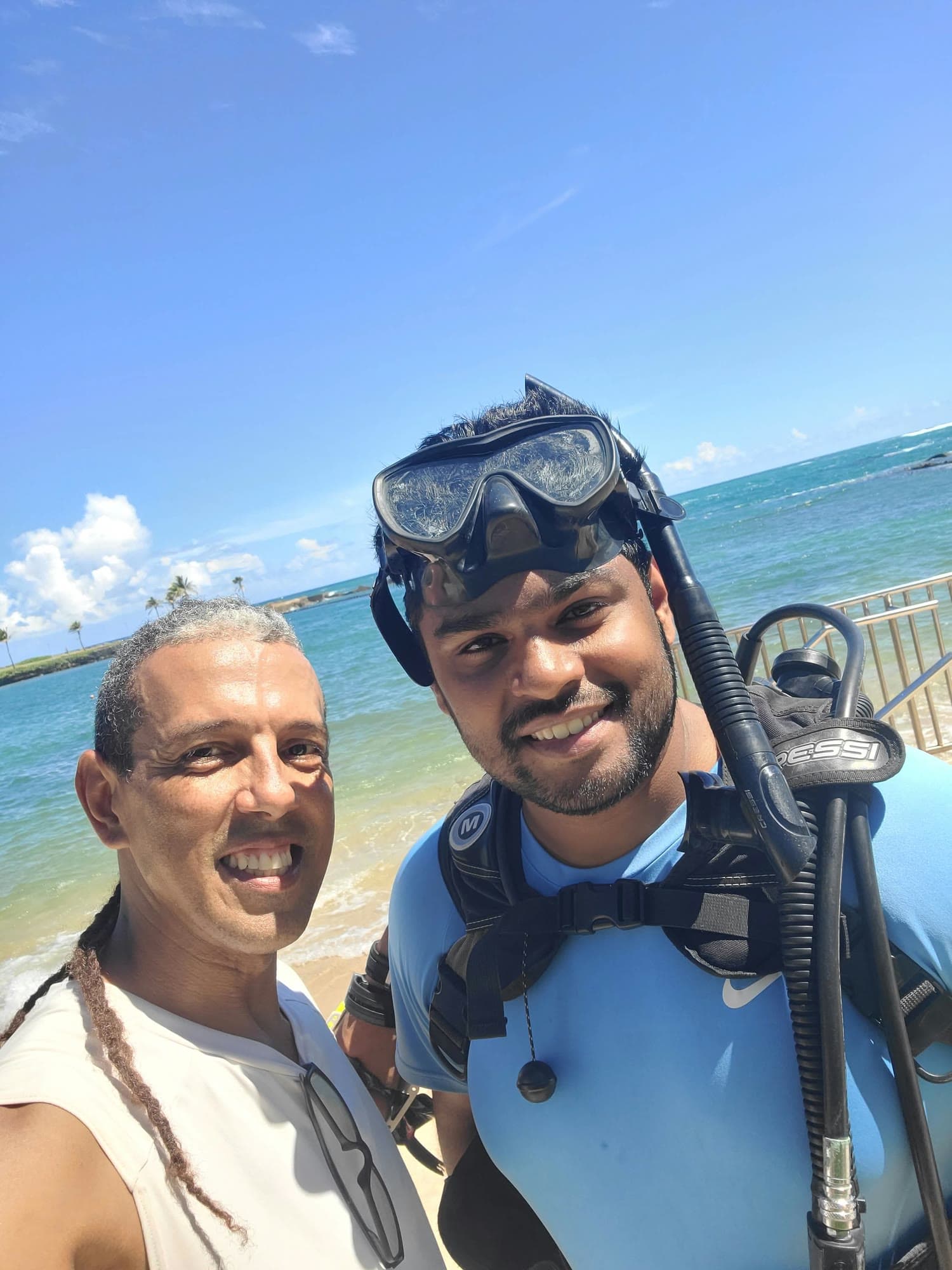 Jesús with a guest in scuba gear on the beach before the dive