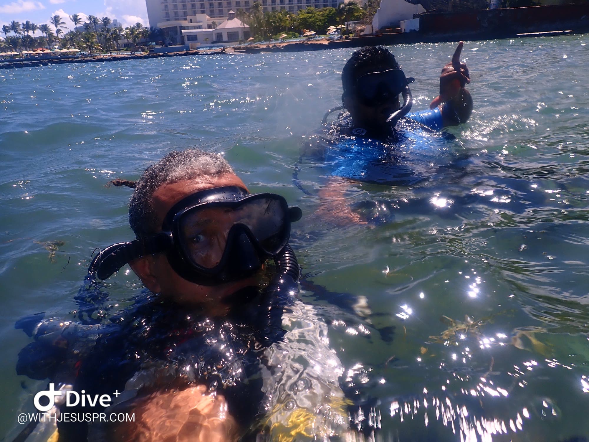 Jesús and a first-time diver at the surface off Escambrón, Caribe Hilton behind