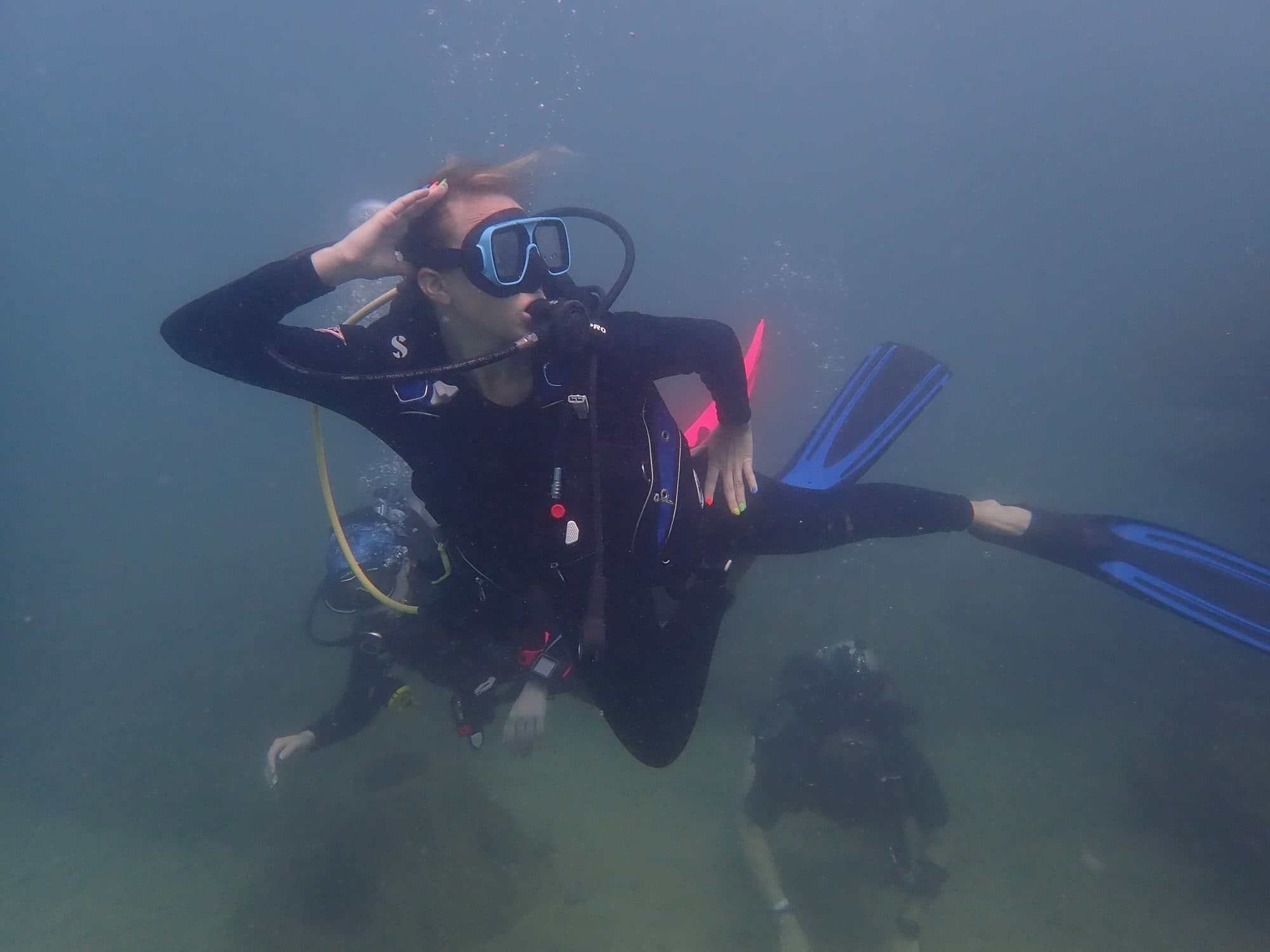 Diver saluting the camera above the sandy bottom