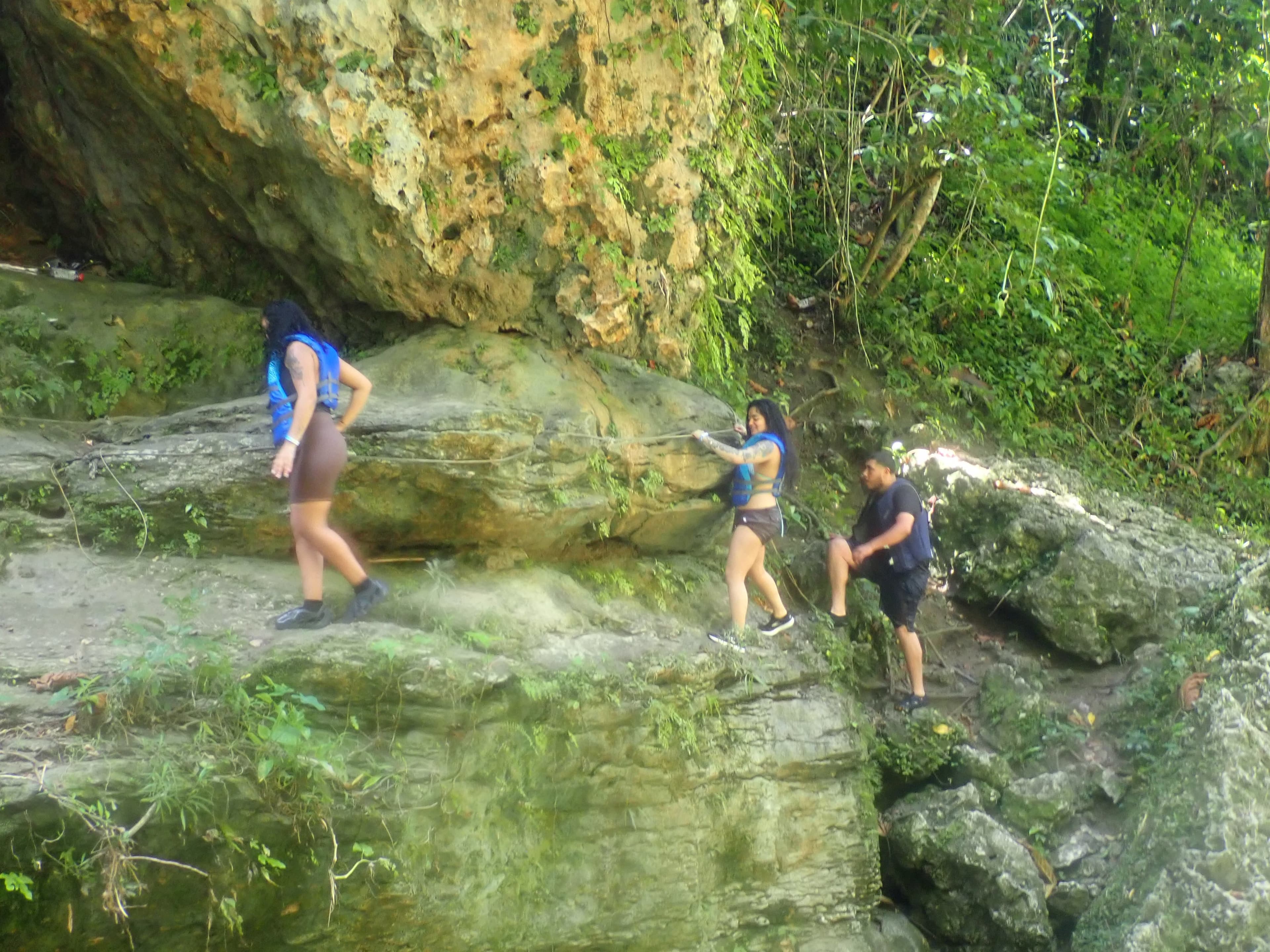 Hikers scrambling up river rocks