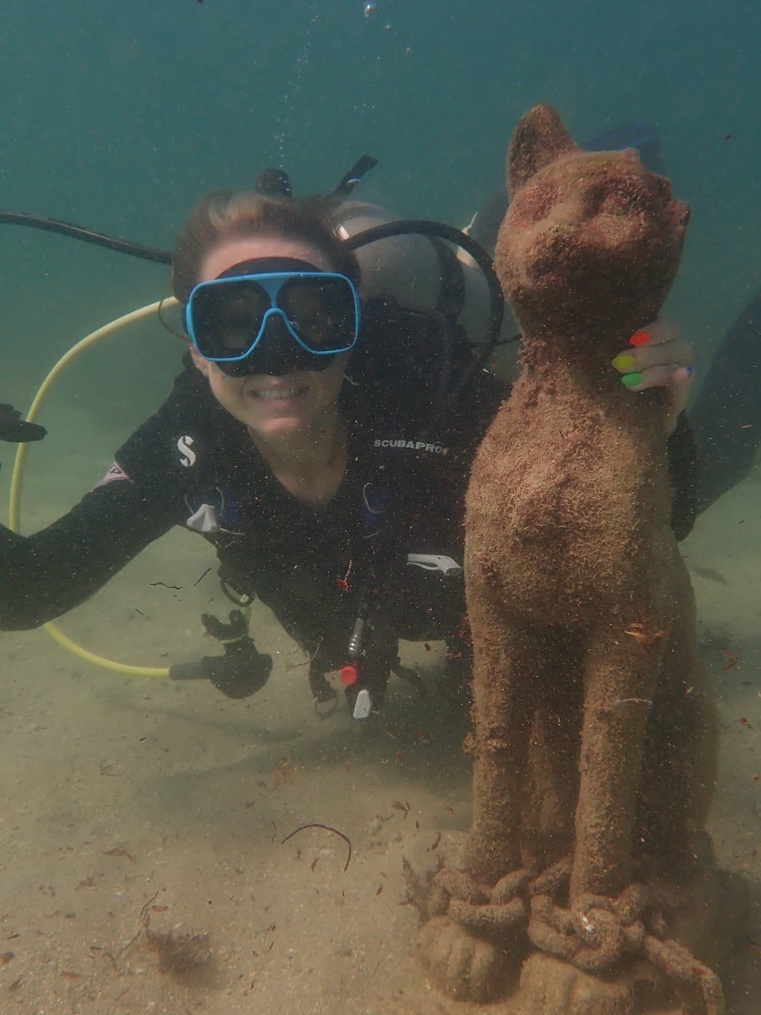 Diver posing beside an underwater statue